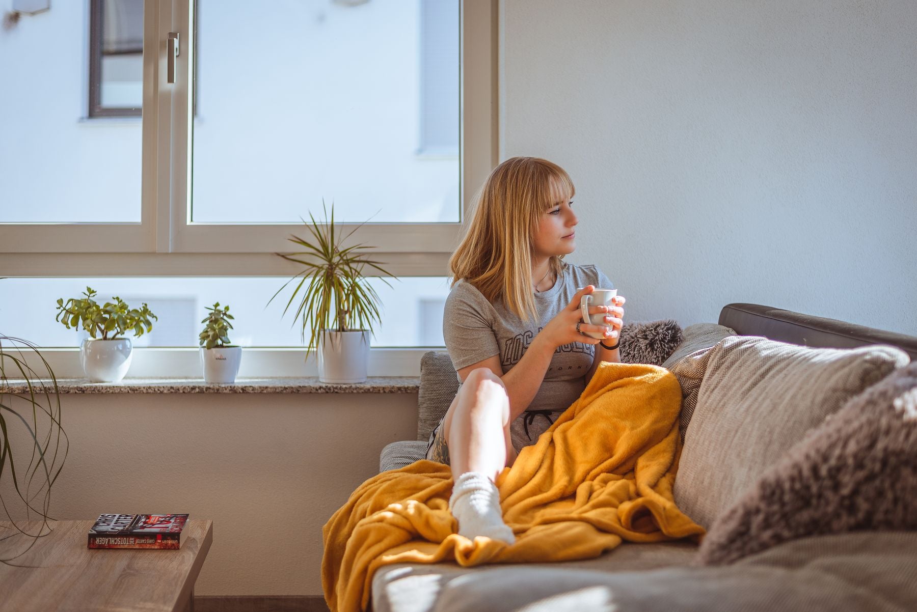 Kvinde med kaffekop i sofaen ved vinduet